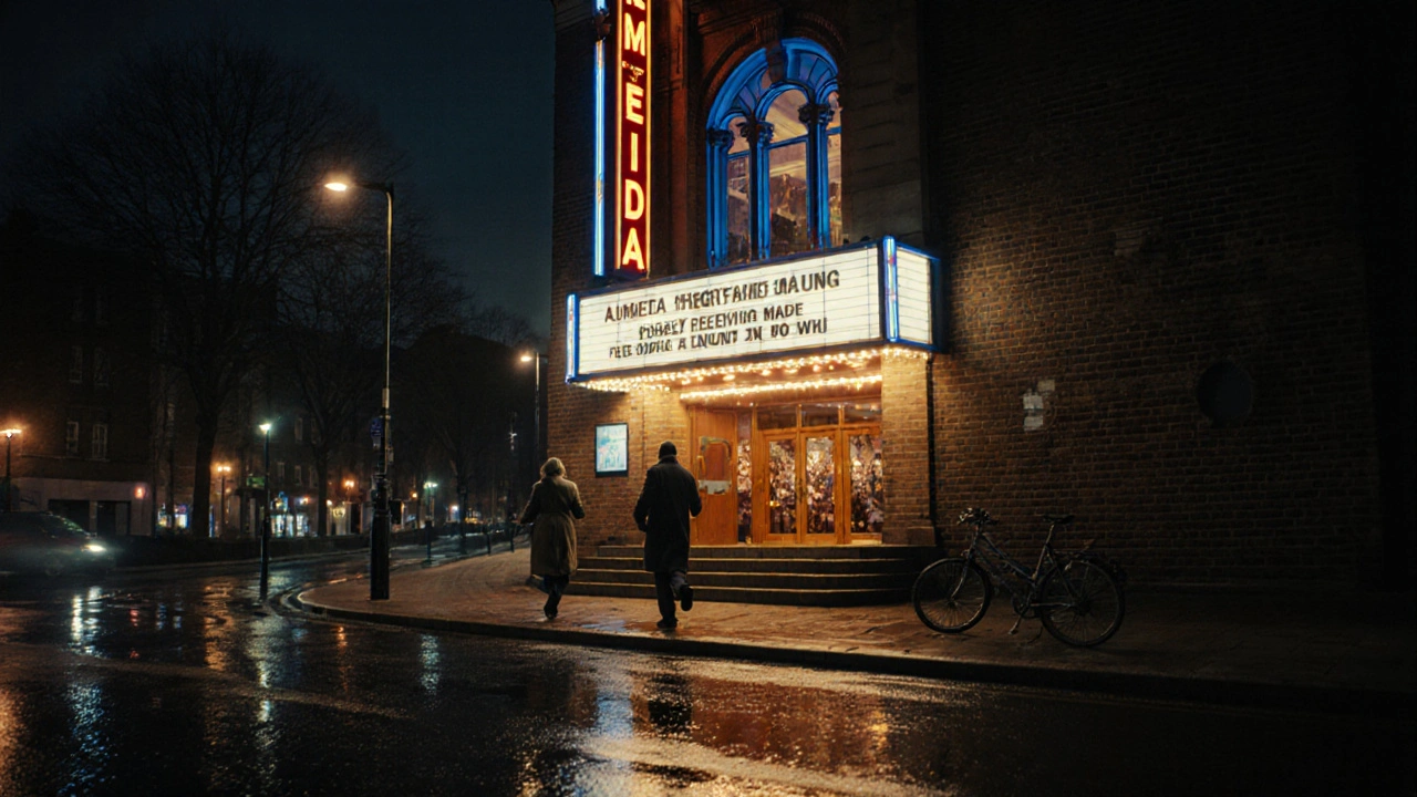 Almeida Theatre entrance at night, couple ascending steps under glowing marquee, wet pavement reflecting light.