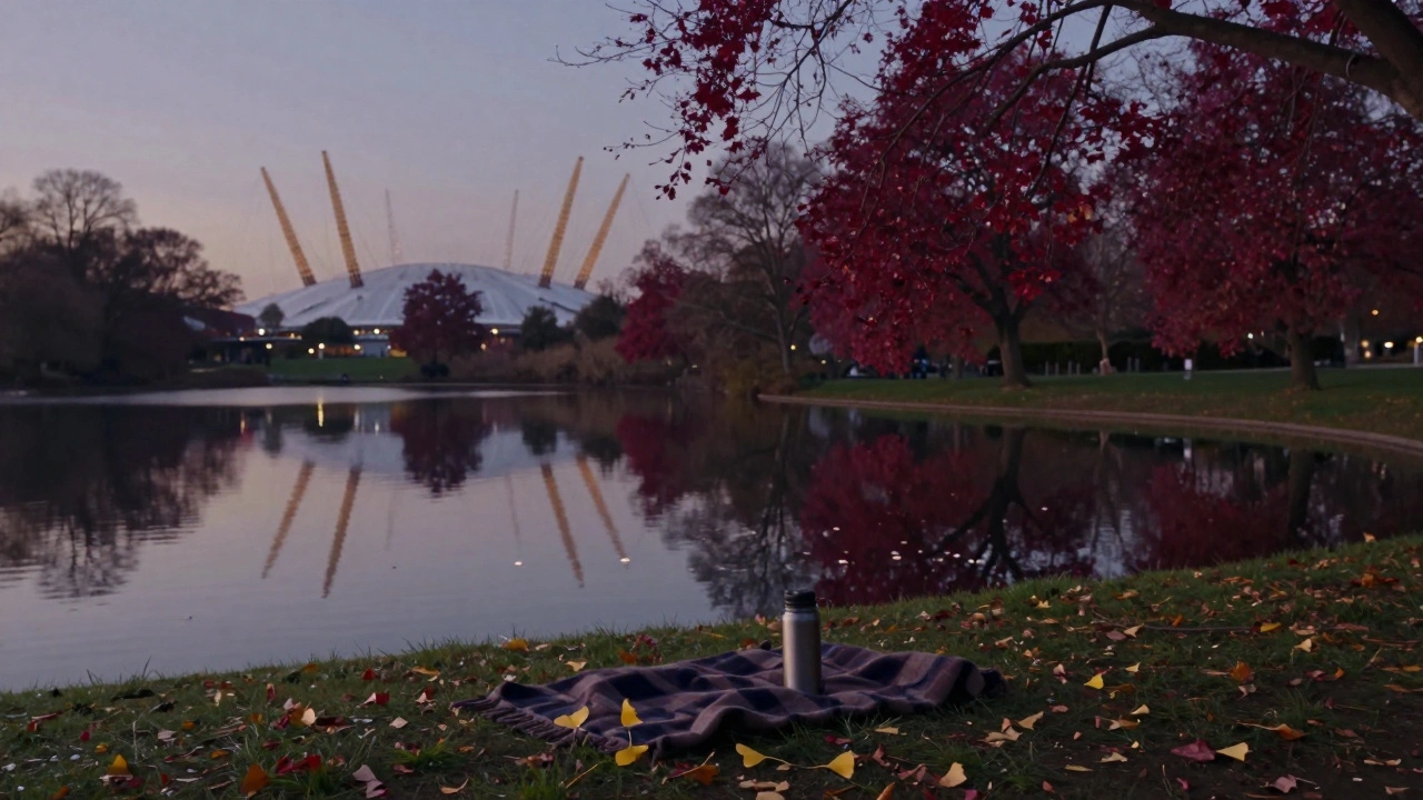 Deep red liquidambers mirrored on Victoria Park’s lake at dusk, with a thermos on the grass.